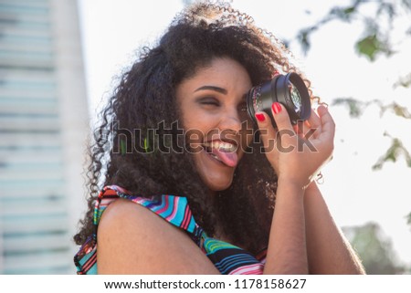 Black woman holding a camera len outside