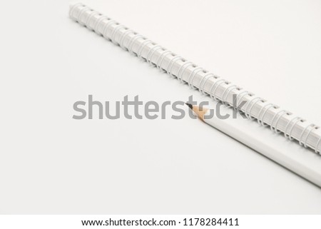 White pencil with white spiral notebook on white background.