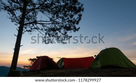 Outdoor travel camping vacation in the sunrise landscape. High-quality stock image of camping tent in the sunrise on mountain and forest. Adventures travel camp tourism and tent under pine forest
