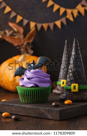 Halloween treats: cupcake, gingerbread cookie shaped as bat and witch hats made of wafer cups. Festive sweet food concept with copy space.