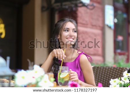 Young woman drinking fresh lemonade in cafe