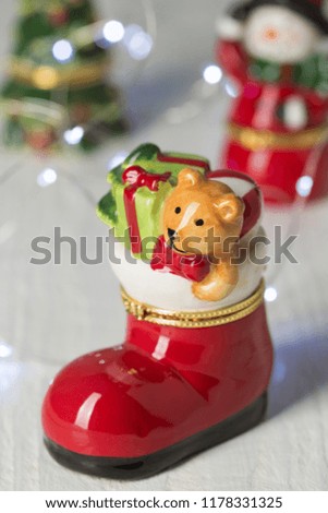 Christmas decorations on the table, in the foreground a red shoe with Christmas toys and a glowing garland, concept