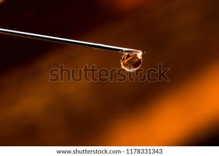 Orange drop on the needle of the syringe is macro