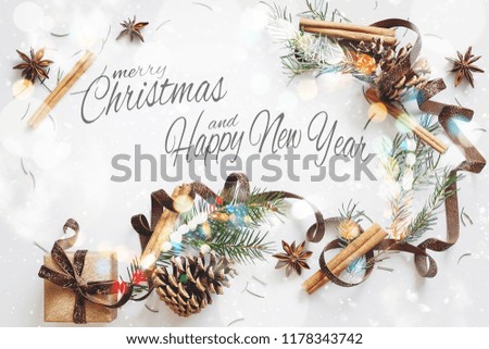 Christmas composition. Gift box, ribbon, fir branches, cones, anise, cinnamon on white background. Flat lay, top view with sign merry christmas and happy new year
