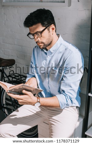 handsome architect with bristle reading book in office