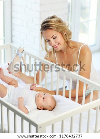 Mom and her baby 2 months in a baby cot