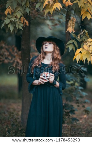 Beautiful witch posing in the autumn forest