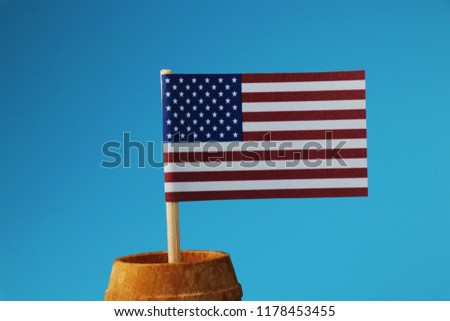 A detail on national flag of united states on wooden stick on blue background. Small national flag