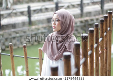 Cute Asian girl wearing red hijab in the park for portraiture shoot.