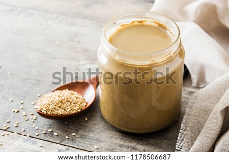 Tahini and sesame seeds on wooden table. 
 Royalty-Free Stock Photo #1178506687