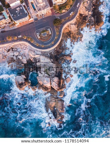 Top down drone shot of some rocks, road and a tidal pool in Seapoint, Cape Town. Royalty-Free Stock Photo #1178514094