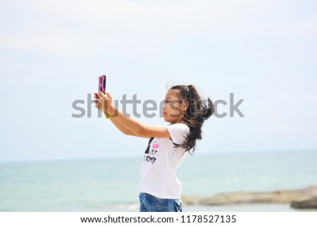Little girl taking selfie by  smartphone on the beach. Girl is a happy and relax in the holiday.