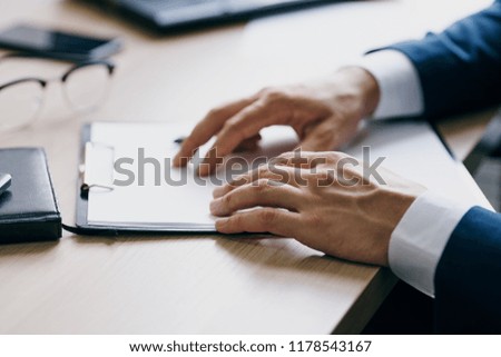 A folder with a sheet of paper and men's hands on a table                            