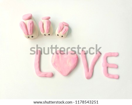 Sweet family rabbits and love text made from pink and white plasticine clay on white background, beautiful decoration dough