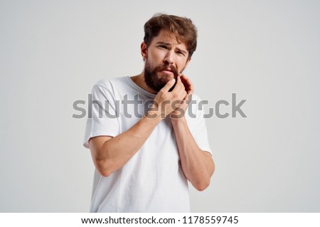 a man with a beard touches his face with a toothache                           