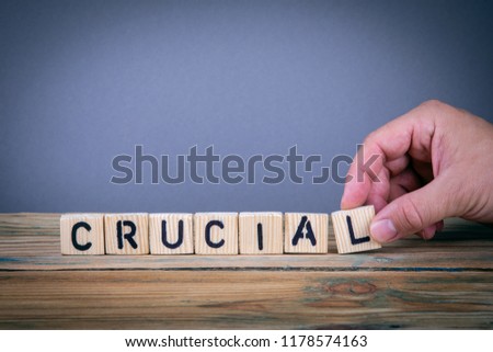 crucial, wooden letters on the office desk, informative and communication background