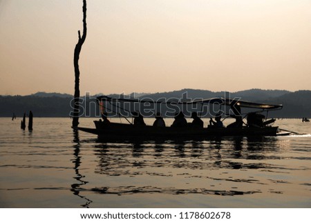 Silhouette tourist boat on the river at Sangkhla Buri is a district in the Kanchanaburi Province in western Thailand