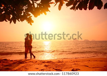 Red toned picture of a couple on a tropical beach at sunset
