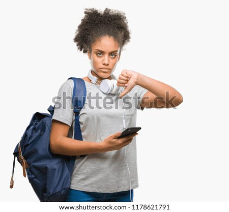 Young beautiful afro american student woman holding backpack over isolated background with angry face, negative sign showing dislike with thumbs down, rejection concept