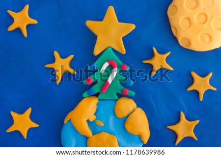 Christmas tree with big christmas star, ornaments and candy cane on planet Earth. Scene is made out of play clay. Close up.