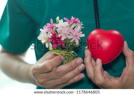 Physician/doctor in green uniform with black stethoscope holds red heart and bouquet of tiny flowers. healthcare concept Royalty-Free Stock Photo #1178646805
