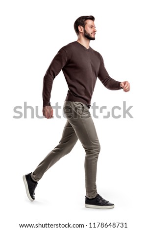A young bearded man in a side view walks fast on the verge of running on a white background. Fast moving. Reaching goals. Getting close to success. Royalty-Free Stock Photo #1178648731