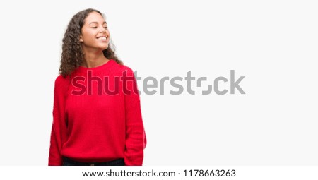 Young hispanic woman wearing red sweater looking away to side with smile on face, natural expression. Laughing confident.