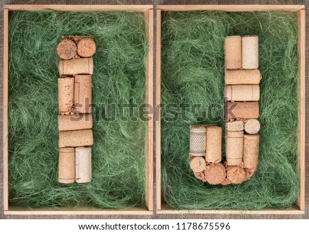 Alphabet letter I and  J  made of  wine corks on green background in wooden box. ABC set  