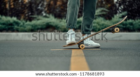 Cropped view of a stylish man in white sneakers and green pants with a skateboard, on a yellow crosswalk. Royalty-Free Stock Photo #1178681893