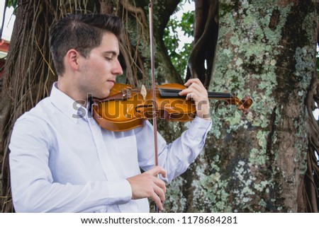boy playing violin in nature