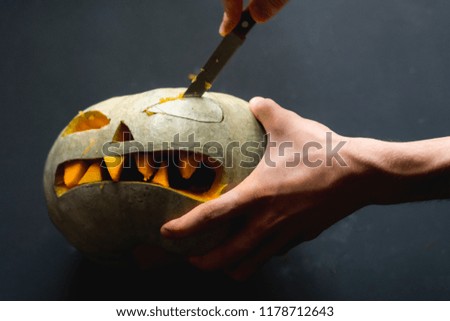 making cutting a pumpkin jack o lantern with carved teeth for halloween concept