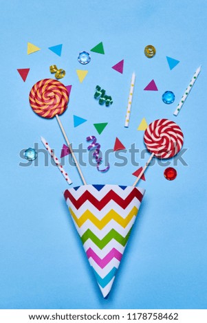 Birthday cap with balloons lollipop and confetti on blue background