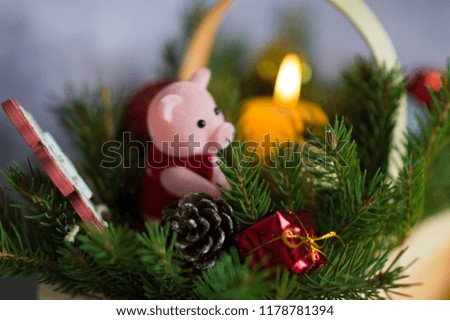 Christmas composition. A statuette of the new year of 2019 - a pig with Christmas decorations in a basket sitting on sprigs of spruce with gifts, toys and candles on the background