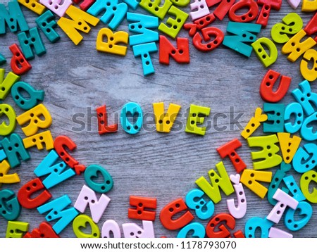 Valentine concept, colorful button alphabets made from plastic with letters for the word "LOVE" on the light grey wooden background