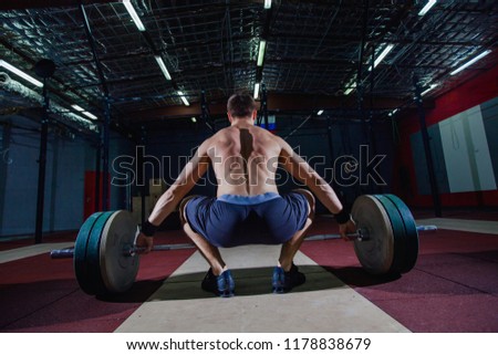 Muscular fitness man preparing to deadlift a barbell over his head in modern fitness center.Functional training.Snatch exercise.