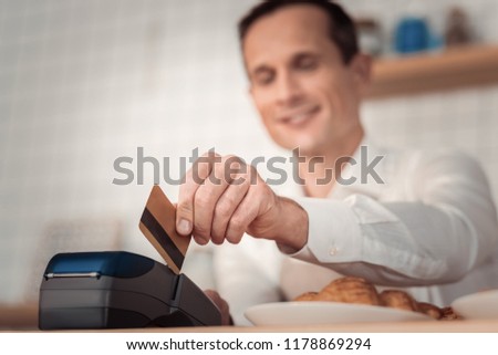 Financial operation. Selective focus of a credit card being in use by a nice joyful man while making non cash payment