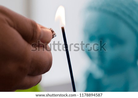 lighting a incense with Buddha figure in the background