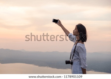 People side view,photographer woman take photo with old camera.Asian traveler female sightseeing with mirrorless camera against sunset background. Travel and Photographer concept.