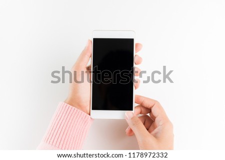 Woman hand holding white mobile phone smartphone on white table background.