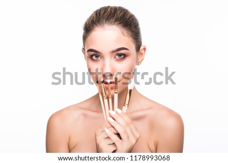 Portrait of young pretty woman hiding face behind makeup brushes