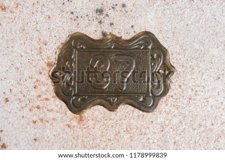 Old brass home number sign #37 on concrete background. Copy space for text