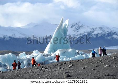Tourist taking picture of the huge iceberg at Jokulsarlon glacier lagoon during winter in Iceland.