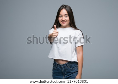Young woman show thumb up and wearing jeans and with isolated gray background
