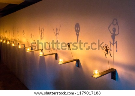 Fabulous shadows of spider, skeleton, bat is reflected on wall from flame of candles standing in row. Black Ghost theatre of shadows, Holiday Halloween.