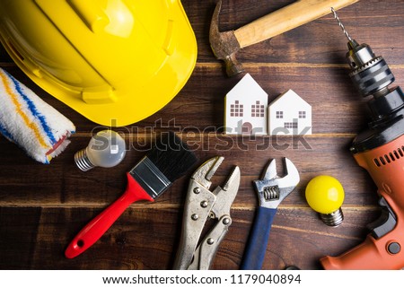 Paper white house toy and construction tools on wooden background with copy space.Real estate concept, New house concept, Finance loan business concept, Repair maintenance concept. Royalty-Free Stock Photo #1179040894