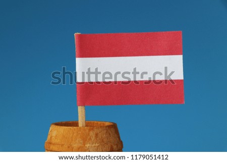 A detail on paper austria flag on wooden stick in wooden barrel. Blue background