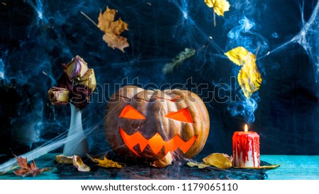 Halloween photo of table with pumpkin, burning candle, cobweb