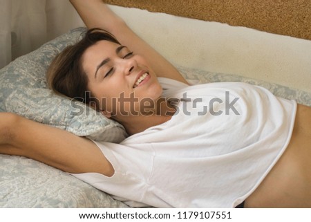 Happy woman waking up stretching her arms in bed