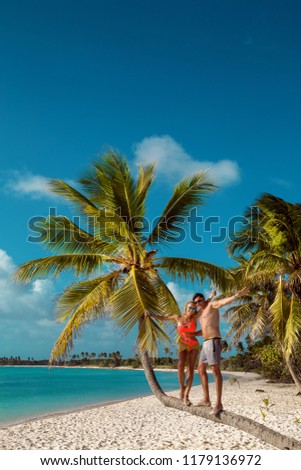 Beautiful woman and man in love on the tropical Caribbean beach. Young couple on a caribbean palm tree. Dominican Republic, Punta cana, Saona Island - Mano Juan Beach. Luxury travel. Vacation. 