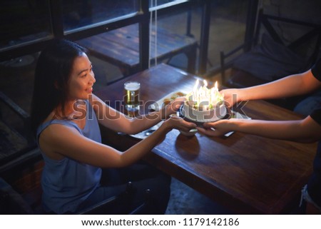 A picture of a cheerful girl looking at a birthday cake from his friend.